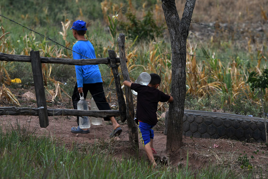 Children carry bottles of water near Los Laureles reservoir, close to the Honduran capital of Tegucigalpa, during a drought caused by climate change. (Getty/Orlando Sierra/AFP)