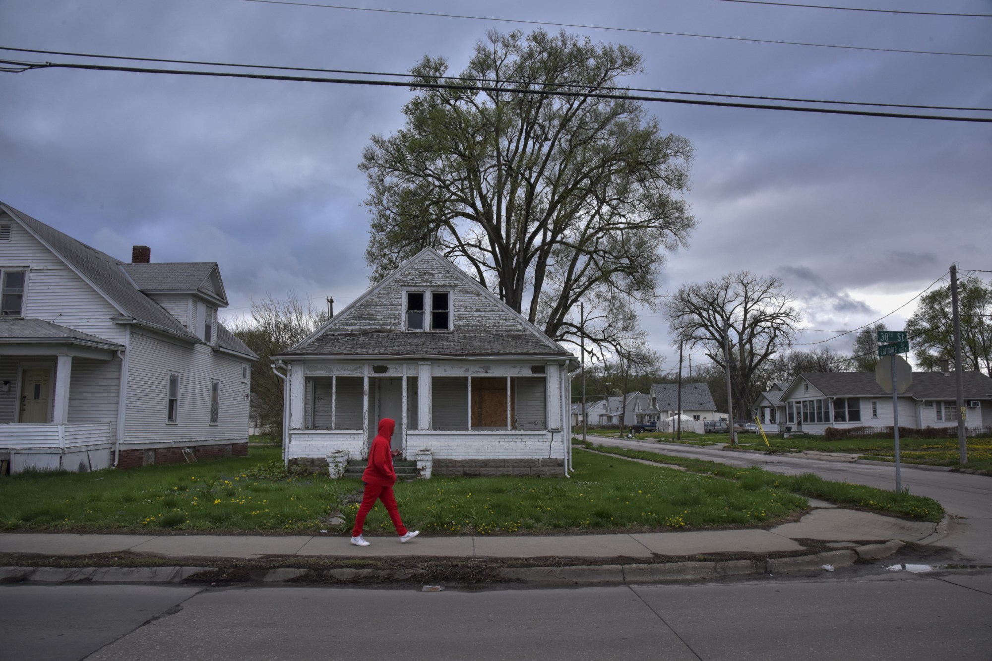 A pedestrian passes in front of a shuttered house in Omaha, Nebraska on a cloudy evening on Thursday, May 3, 2018. (A pedestrian passes in front of a shuttered house)