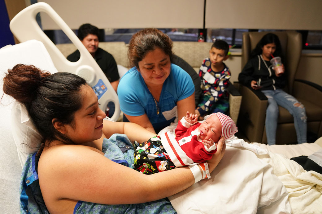 A woman is handed her newborn son by her mother in a hospital in St. Paul, Minnesota, December 2019. (Getty/Anthony Souffle/Star Tribune)