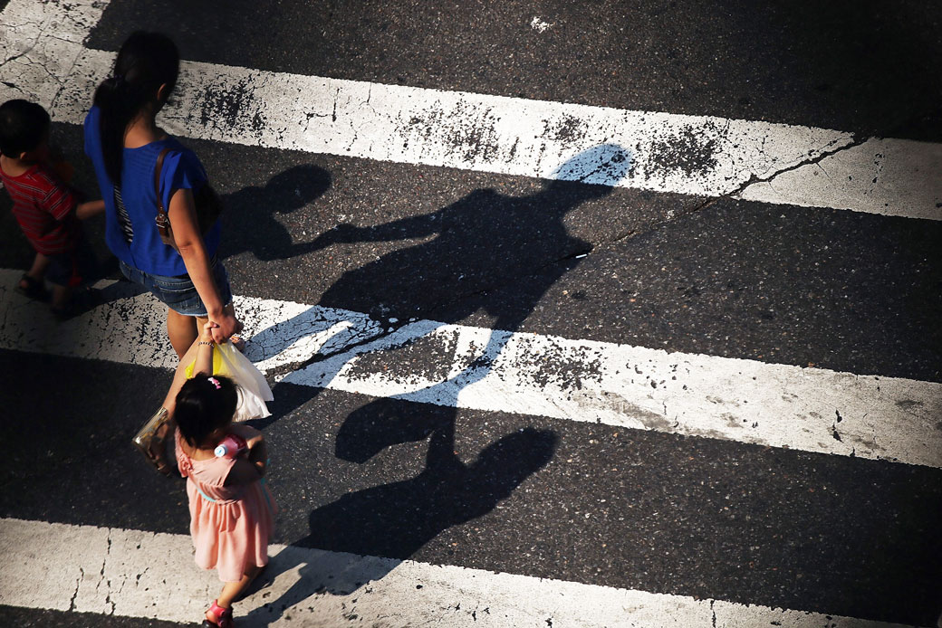  (A woman with two young children crosses a street in New York City, August 2013.)