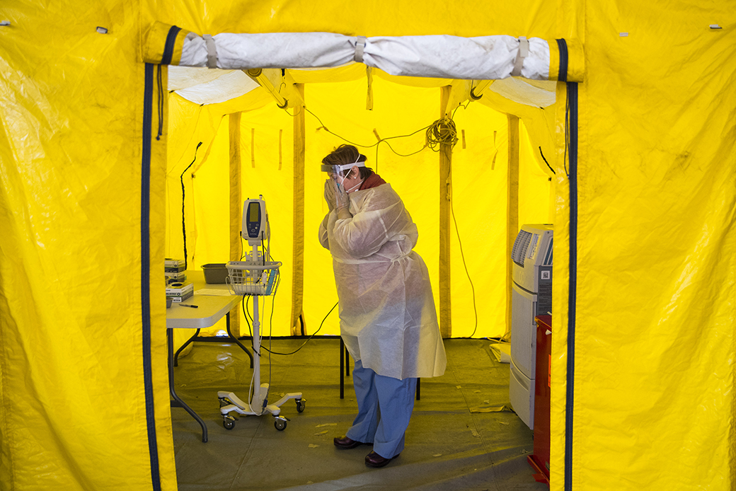 A nurse practitioner puts on protective gear in a tent in a hospital parking lot before testing a possible coronavirus patient in Newton, Massachusetts, on March 16, 2020. (Getty/Adam Glanzman)