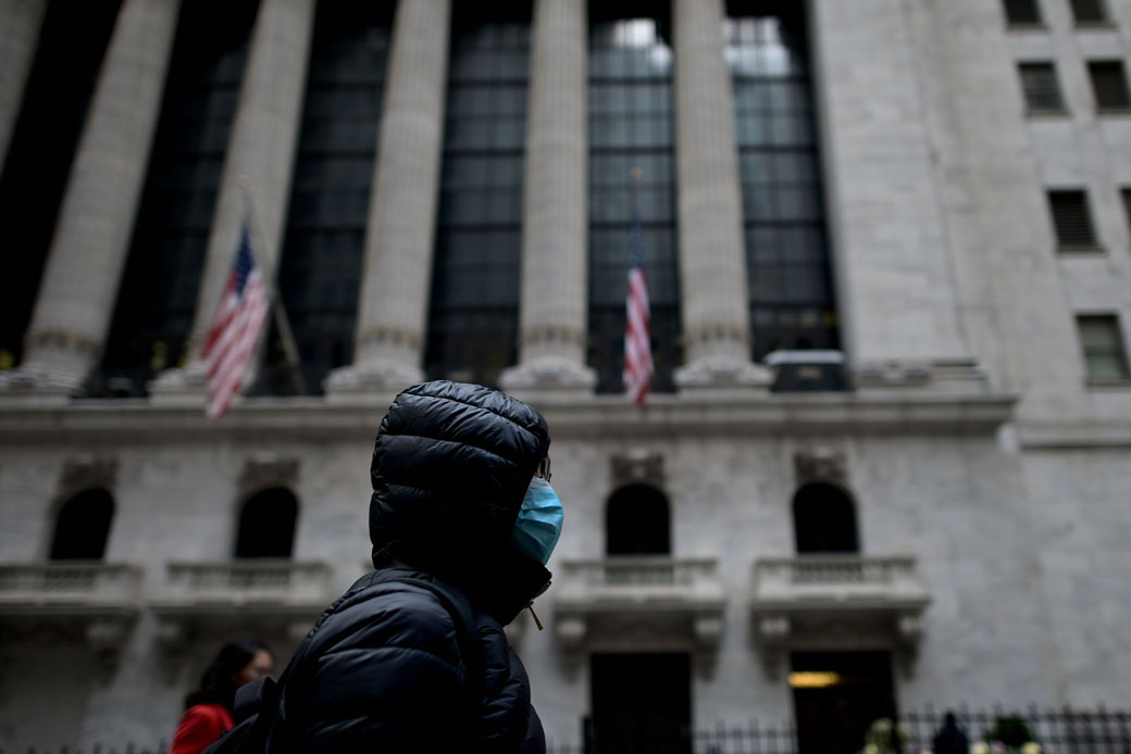 A woman wearing a face mask passes by the New York Stock Exchange in New York City, February 3, 2020. (Getty/Johannes Eisele/AFP)