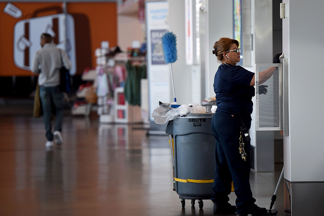 A woman wipes down common areas inside an airport, March 2020. She says disinfecting things such as doors, handles, trash can lids, and anything else that people commonly touch was a routine part of her day even before the coronavirus concerns. (Getty/Brittany Murray)