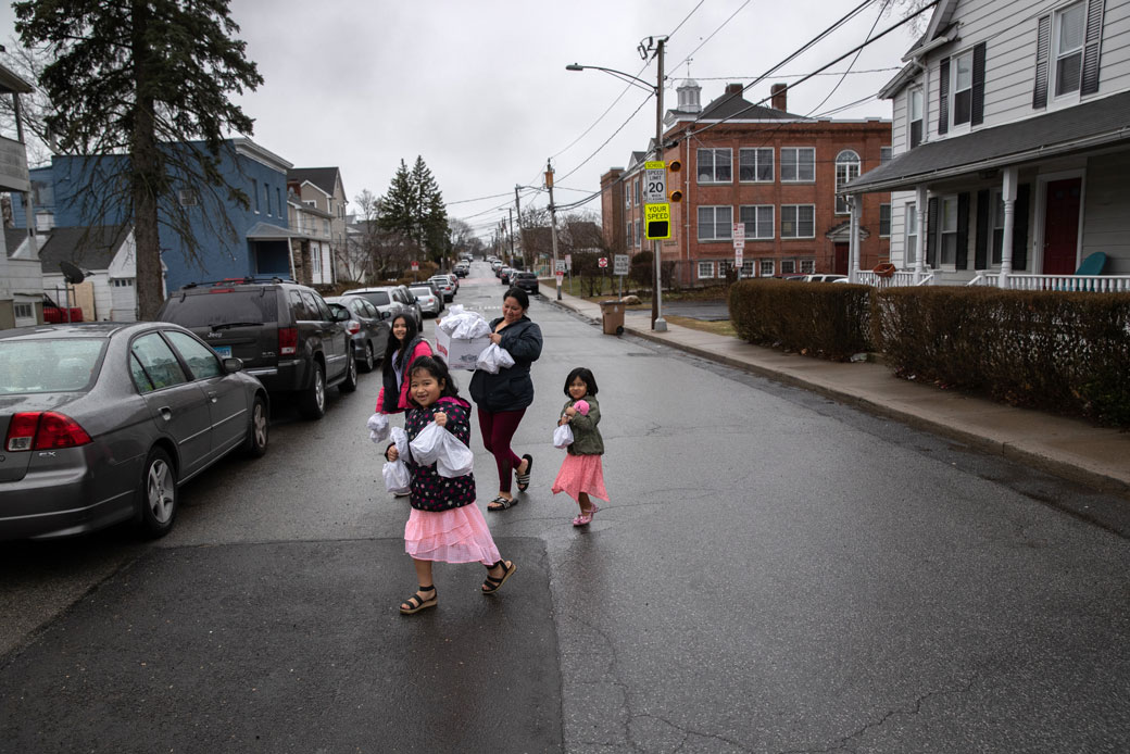 Families in Stamford, Connecticut, carry home free bagged meals given out as part of the city's response to the COVID-19 pandemic, March 2020. (Getty/John Moore)