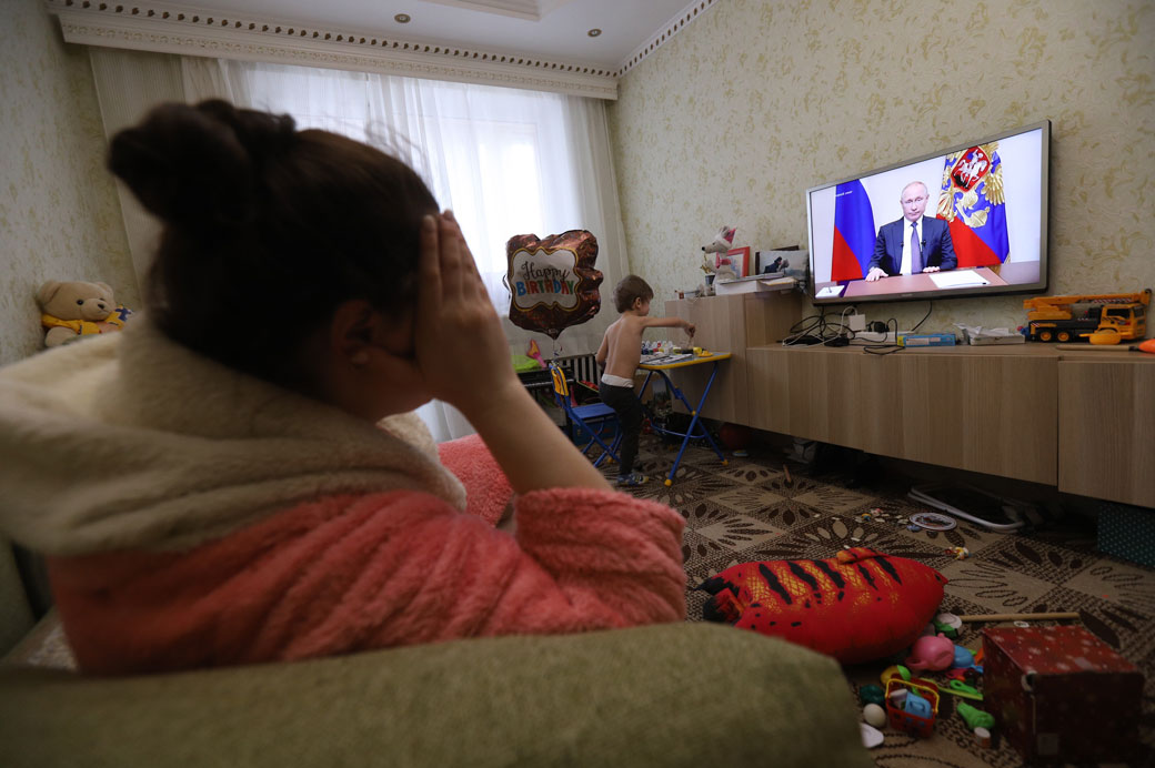 A woman watches Russian President Vladimir Putin addressing the nation about the coronavirus pandemic, March 25, 2020. (Getty/Sergei Mikhailichenko/SOPA Images/LightRocket)