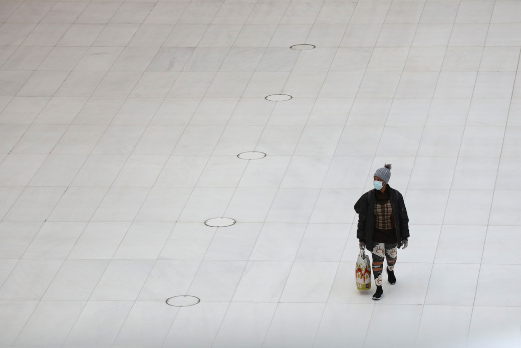  (A woman wearing a mask walks through an empty transit hub in New York City on Easter Sunday, April 12, 2020.)