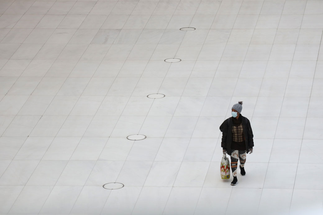 (A woman wearing a mask walks through an empty transit hub in New York City on Easter Sunday, April 12, 2020.)