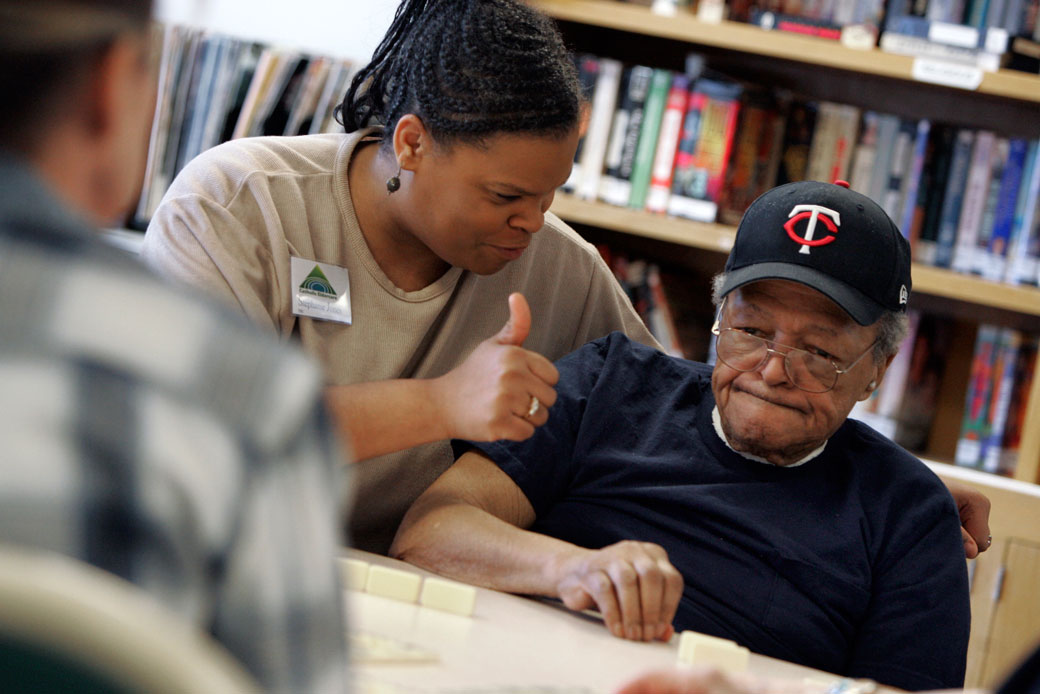 An employee at a Minneapolis nursing home sits at a table with a group of residents playing dominoes, January 2006. (Getty/Star Tribune/Stormi Greener)