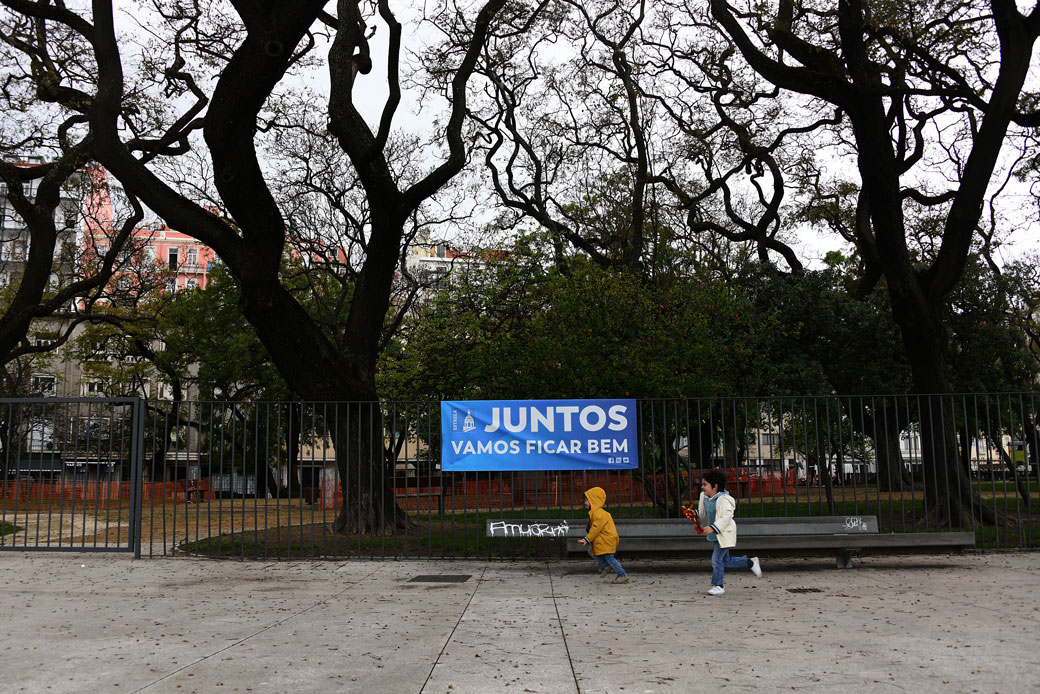 Two children run past a banner that says, 