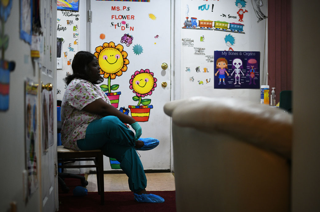 Angelique Speight-Marshall puts on protective gloves and slippers to protect her clients from the coronavirus inside her child care facility, March 2020. (Getty/Astrid Riecken)