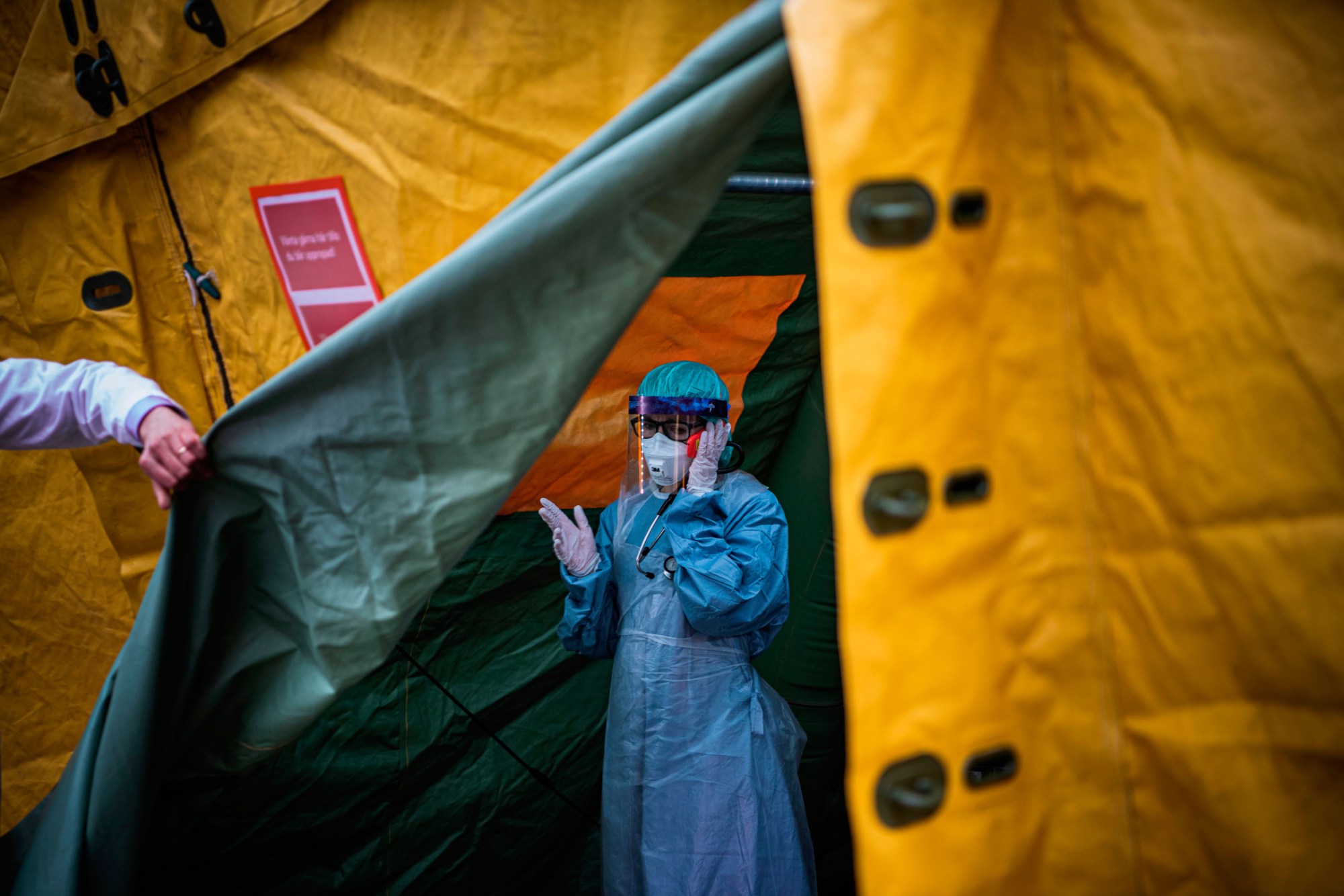 A medical staffer at Sophiahemmet hospital in Stockholm talks on a cell phone while exiting a tent for testing and receiving potential COVID-19 patients, April 2020. (Getty/AFP/Jonathan Nackstrand)