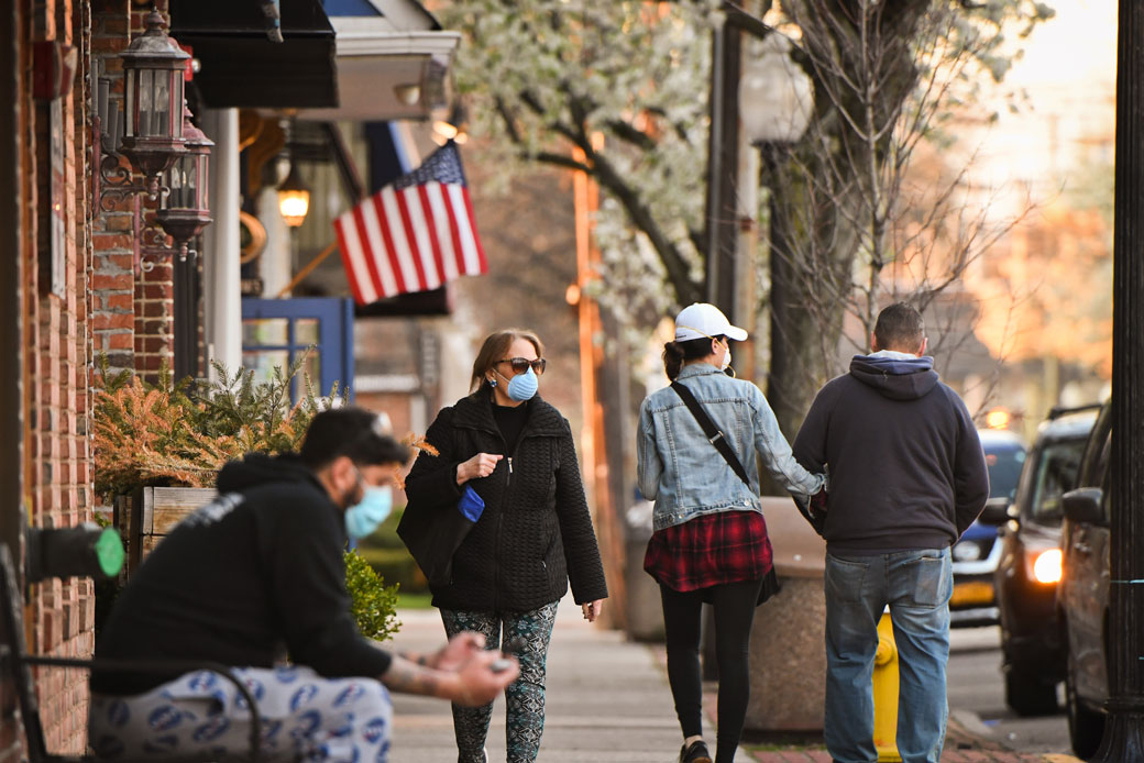 People wearing masks stroll Main Street in Babylon Village, New York, as the sun sets, April 2020. (Getty/Newsday RM/Steve Pfost)