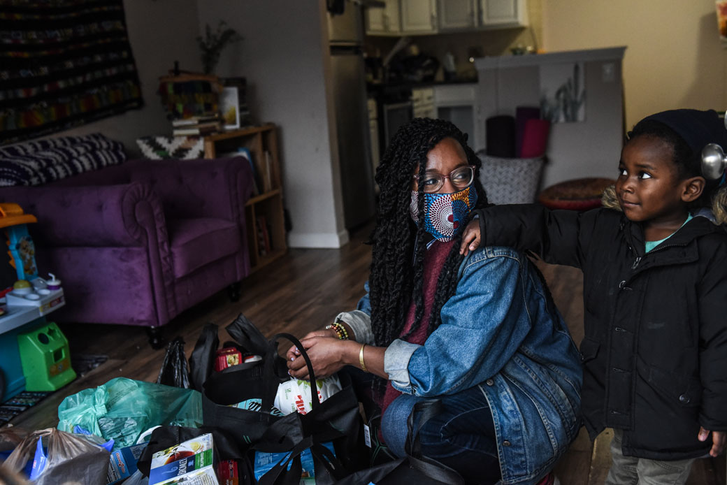A mother looks at her son while unpacking groceries in New York City, May 2020. (Getty/Stephanie Keith)