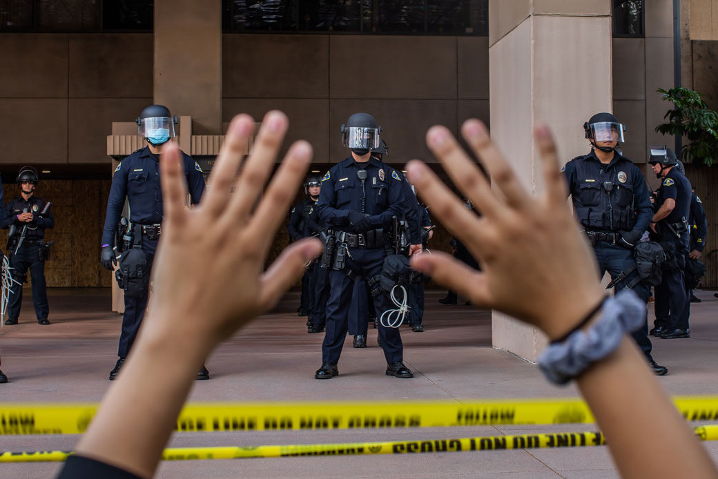 A demonstrator holds her hands up in front of police officers at Anaheim City Hall on June 1, 2020, in Anaheim, California, during a peaceful protest over the death of George Floyd. (Getty/AFP/Apu Gomes)