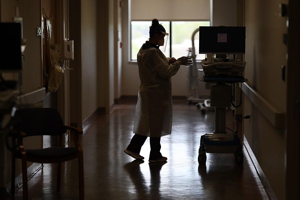 A member of the dialysis team dons personal protective equipment before treating a patient with the coronavirus in the intensive care unit of a Maryland hospital, May 2020. (Getty/Win McNamee)