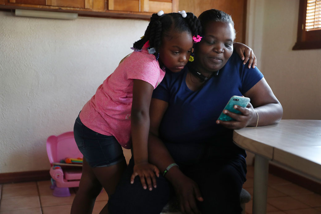  (A woman in Miami spends time looking at videos with her 6-year-old granddaughter after being laid off from her job as a food service cashier in the wake of the coronavirus crisis, March 2020.)