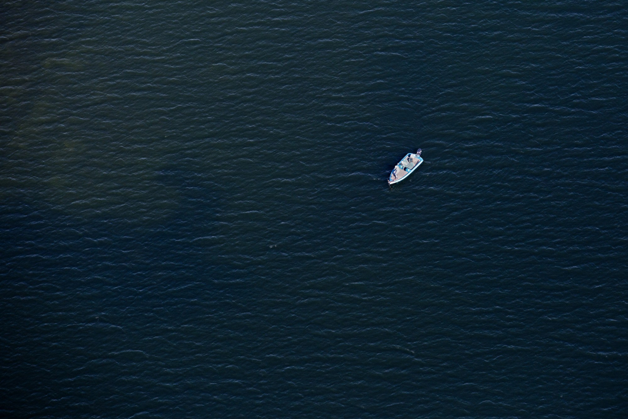 A fisherman stands on the bow of his boat while fishing in Taylor Pond in Auburn, Maine, on May 14, 2015. (Getty/Gabe Souza)