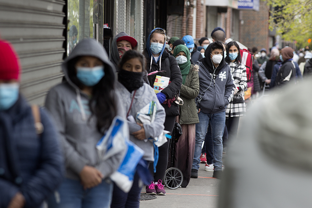 People wearing protective masks form a line to receive free food from a food pantry, May 2020 in Brooklyn, New York. (Getty/Andrew Lichtenstein)
