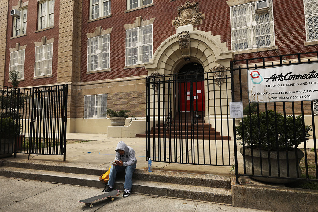 A student sits outside of a closed public school in Brooklyn, New York, April 2020.