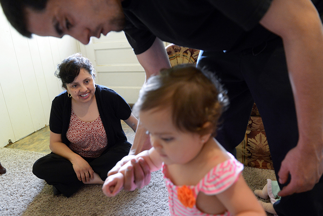 A father helps his 1-year-old daughter walk as a family support worker visits the family's home, May 2013, in Virginia. (Getty/Matt McClain)