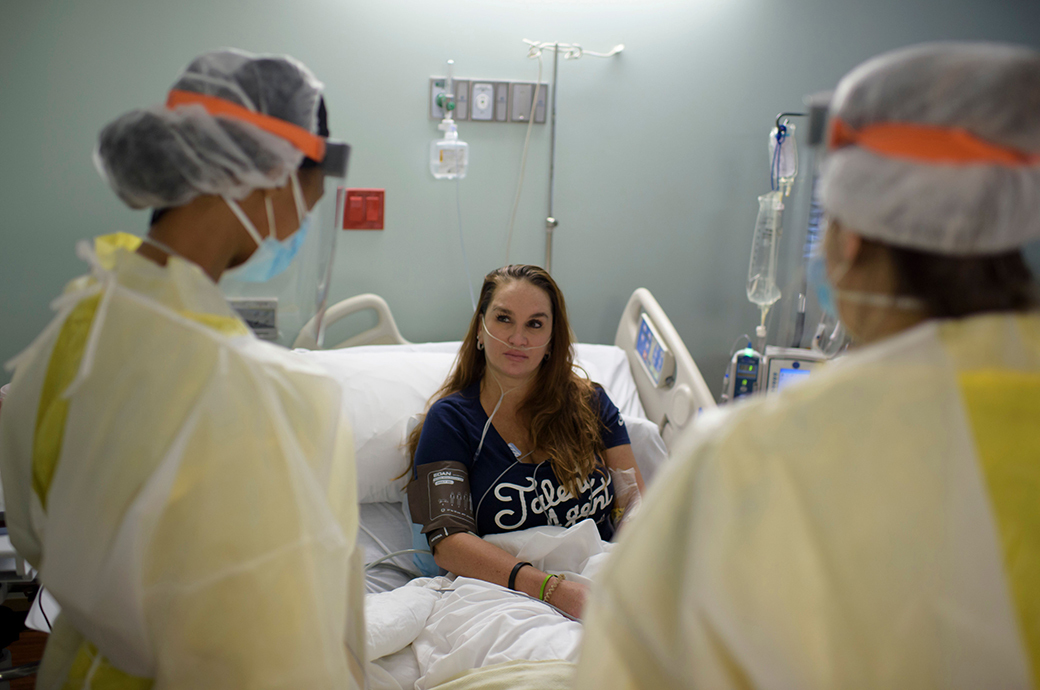 Healthcare workers talk to a patient in the Covid-19 Unit at United Memorial Medical Center in Houston, Texas, July 2, 2020. - Despite its renowned medical center with the largest agglomeration of hospitals and research laboratories in the world, Houston is on the verge of being overwhelmed by cases of coronavirus exploding in Texas. (Photo by Mark Felix / AFP) / RESTRICTED TO EDITORIAL USE
TO GO WITH AFP STORY by Julia Benarrous: 