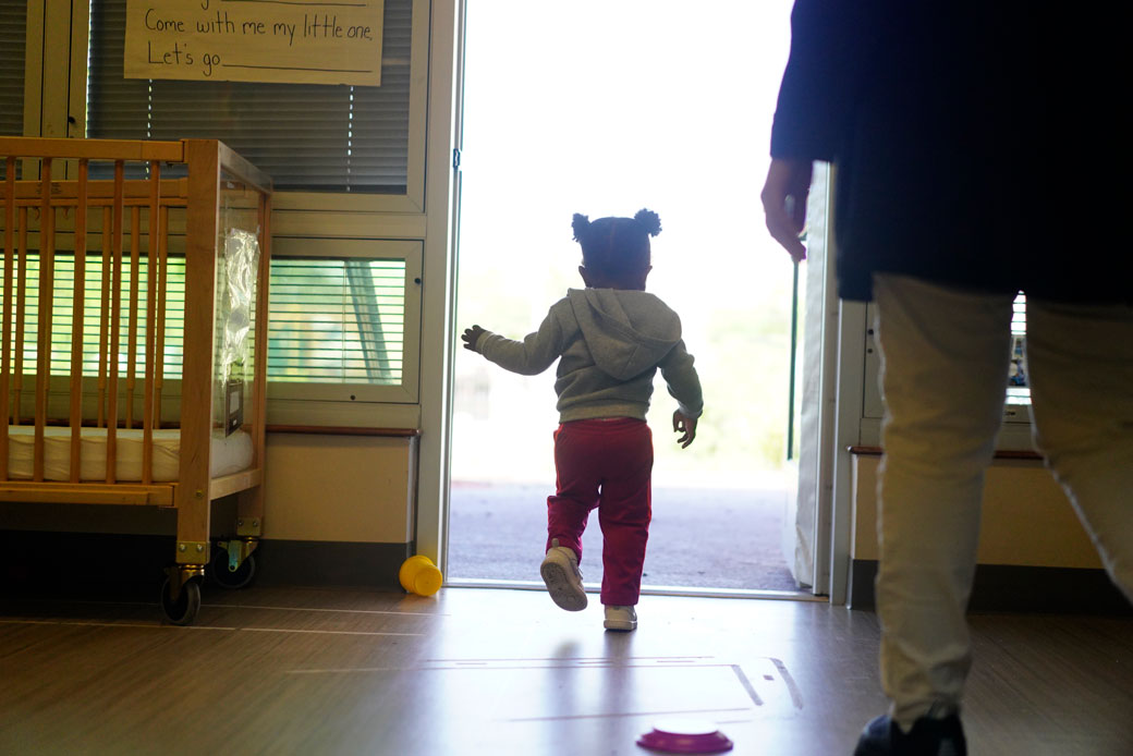  (A toddler walks toward the door at a child care center in Washington, D.C., on May 3, 2019.)