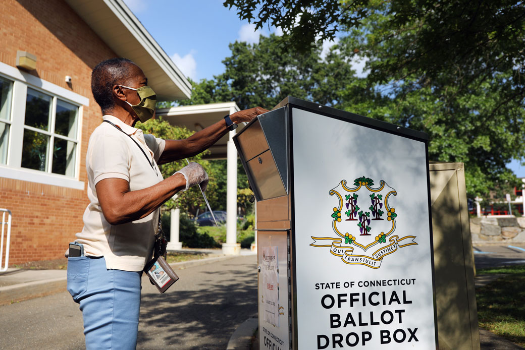  (A woman drops her Connecticut 2020 presidential primary ballot at a secure ballot drop box in Stamford, Connecticut, on August 11, 2020.)