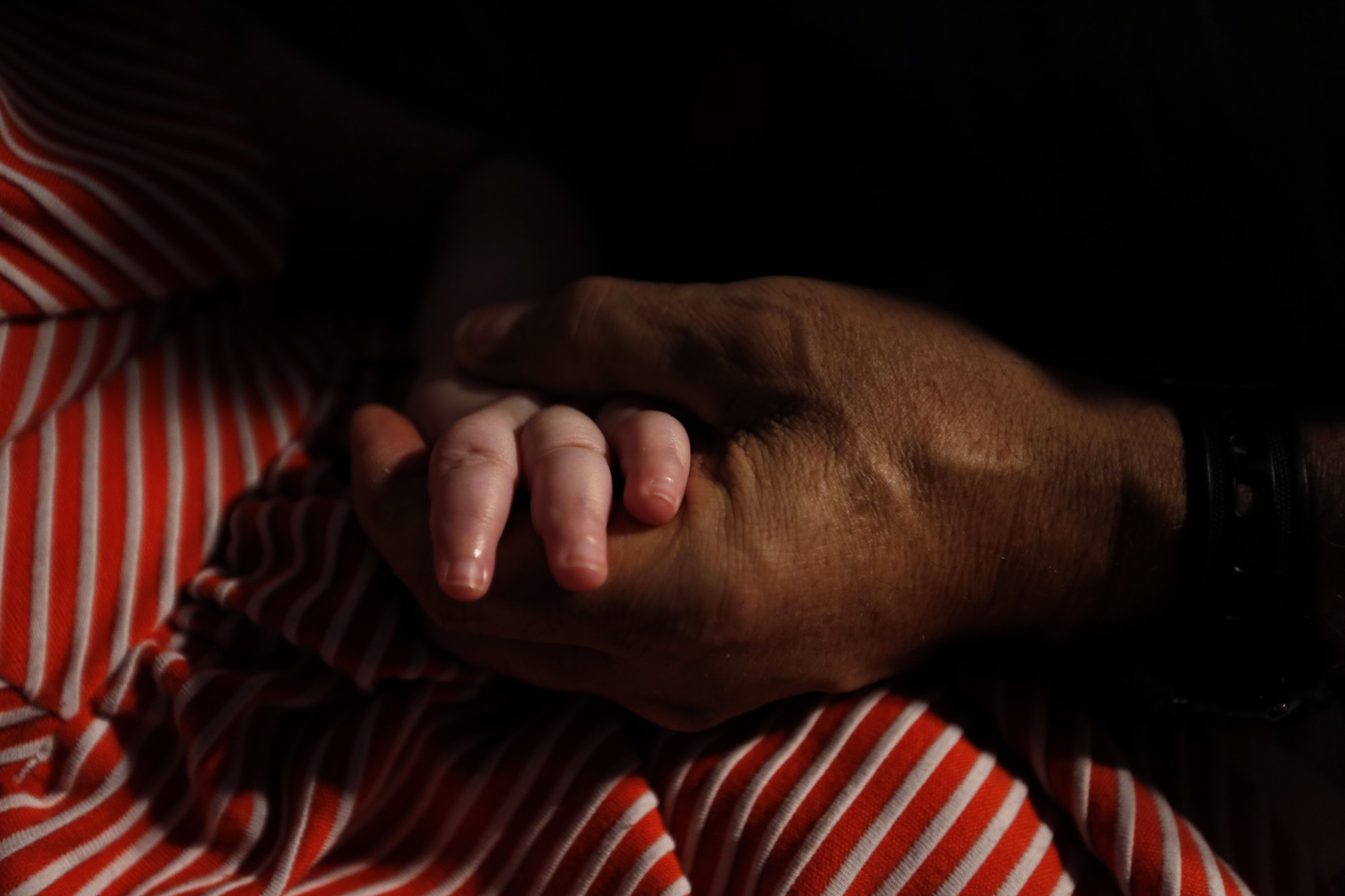 LOS ANGELES, CA - DECEMBER 07: Mohamed Bzeek holds hands with his foster daughter who suffers from microcephaly in their home in Azusa on December 7, 2026. The daughter, who cannot see, hear or speak, mostly responds to the human touch. Bzeek and his wife, who died a few years ago, started taking in critically ill children. He has continued since her death. He has buried 10 foster children and has one biological son, a 19-year-old with dwarfism and brittle bones who is confined to a wheelchair. (Photo by Genaro Molina/Los Angeles Times via Getty Images) (A man holds the hand of his foster daughter in their home in Azusa, California, on December 7, 2016.)