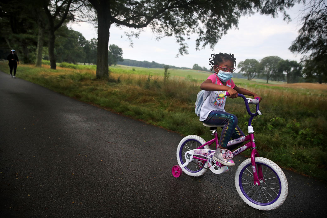 A young girl leads her mother through Franklin Park during their morning exercise routine in Boston, July 2020. (Getty/The Boston Globe/Craig F. Walker)