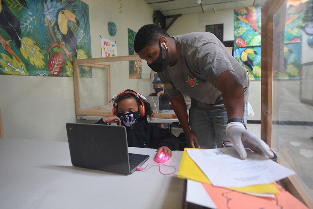 At a learning center in Culver City, Calilfornia, an instructor helps a student with her lesson at a desk separated from others by plastic barriers, September 2020. (Getty/Robyn Beck/AFP)