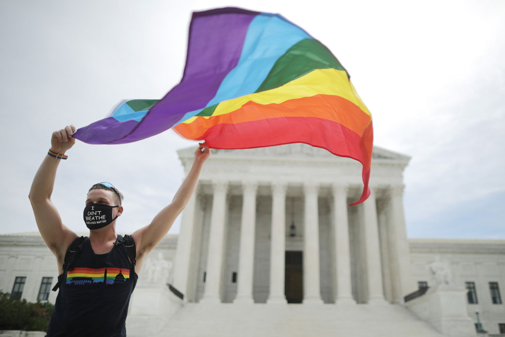 An advocate for LGBTQ rights holds a pride flag in front of the U.S. Supreme Court building in Washington, D.C., June 2020. (Getty/Chip Somodevilla)