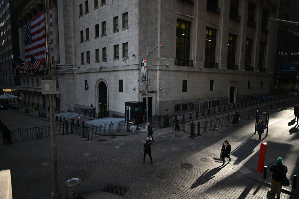 People walk past the New York Stock Exchange on Wall Street in New York City on March 16, 2020. (Getty/Johannes Eisele/AFP)