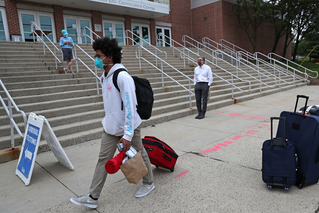 A college student in Medford, Massachusetts, walks past a campus testing center with his luggage on August 27, 2020. (Getty/David L. Ryan/The Boston Globe)