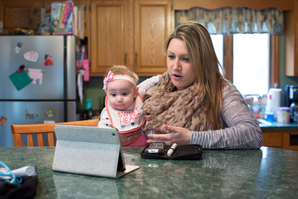 Erica Jensen, with her daughter at her side, videoconferences her doctor in Wilmington, Massachusetts, on March 15, 2016. (Getty/Dina Rudick)