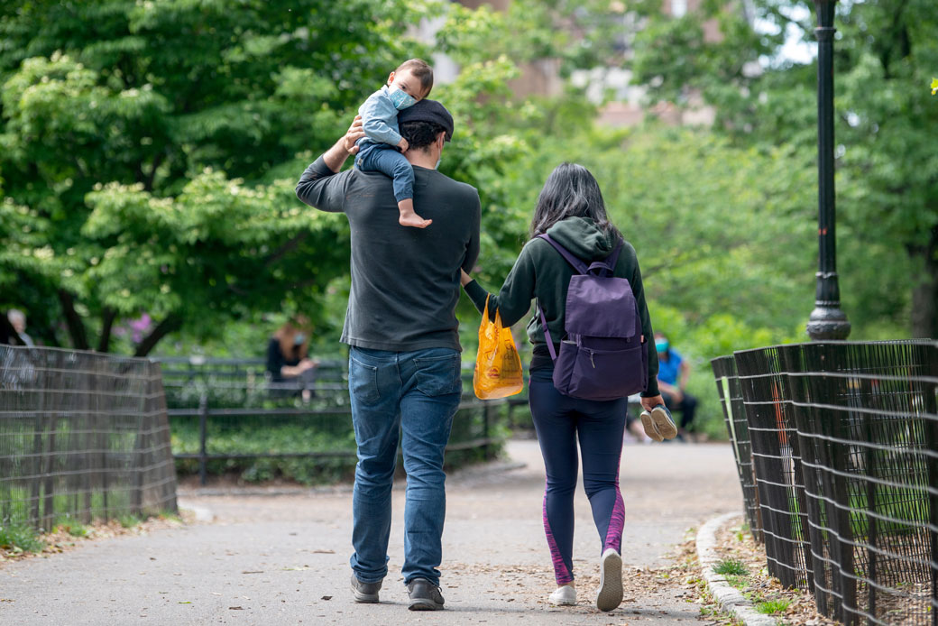 A young child wearing a mask sits on his father's shoulder in Central Park, New York, on May 24, 2020. (Getty/Alexi Rosenfeld)