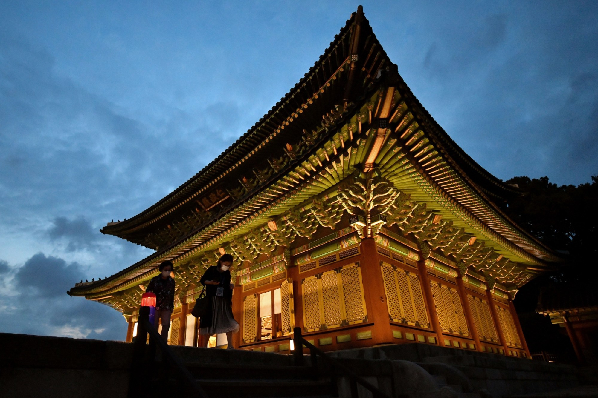 Visitors holding Korean traditional lanterns look around during a 'moonlight tour' at Changdeokgung Palace, a UNESCO World Cultural Heritage site, in Seoul on August 13, 2020. - The annual nighttime special tour to the palace opened on August 13 and will run through September 13. (Photo by Jung Yeon-je / AFP) (Photo by JUNG YEON-JE/AFP via Getty Images)