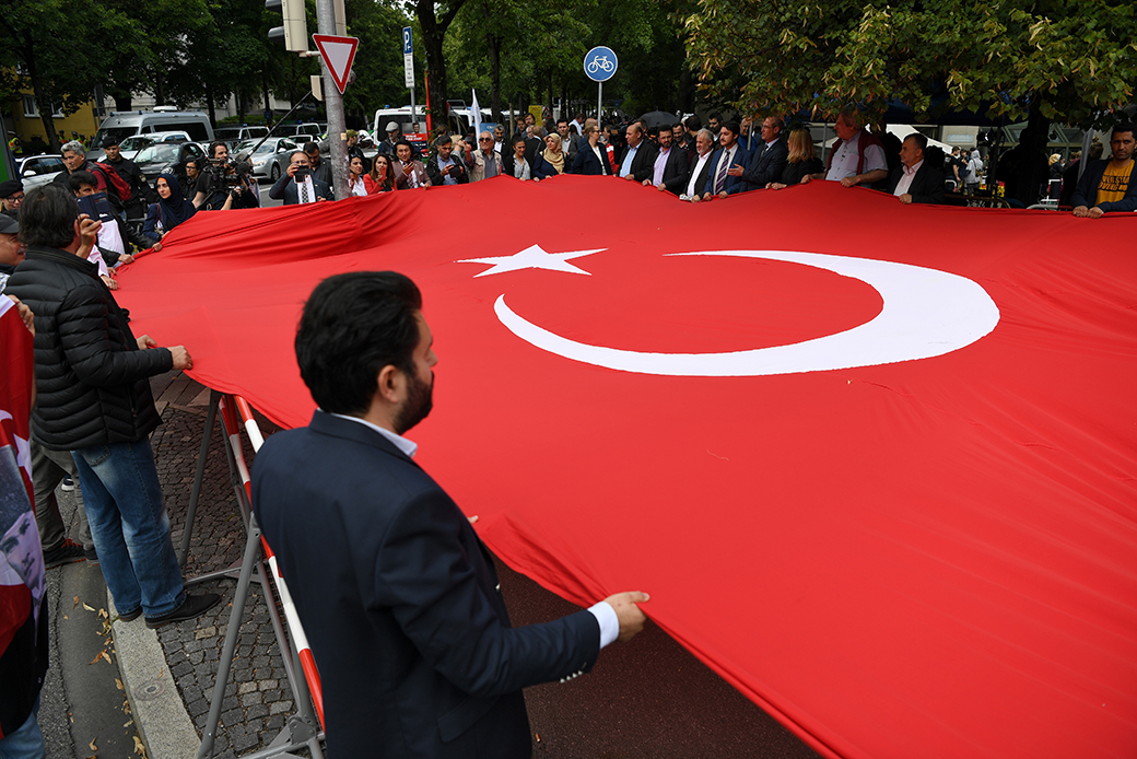 Members of the Turkish community stand in front of the Oberlandesgericht courthouse with a large Turkish flag, 2018, in Munich. (Getty/Andreas Gebert)