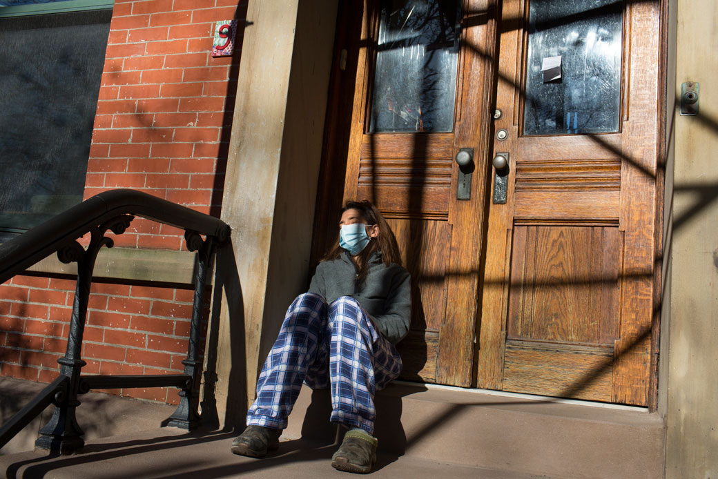 A COVID-19 patient, trying to recover at home, grabs fresh air on the front stoop of her home in Brooklyn, New York, on November 20, 2020. (Getty/Andrew Lichtenstein)