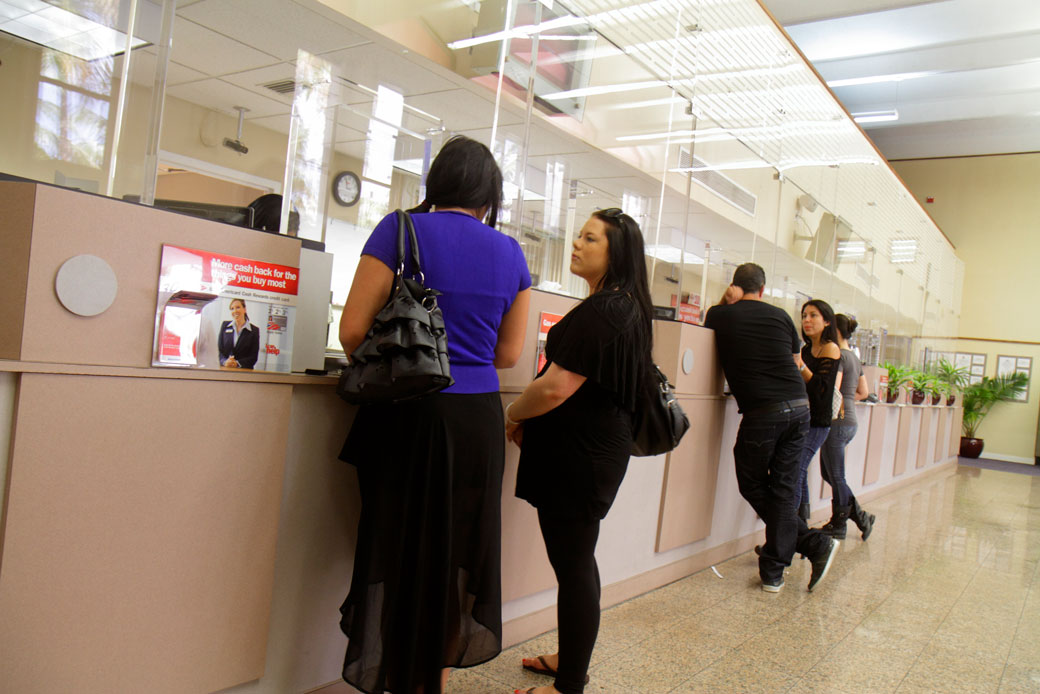  (Customers stand at a teller's window at a bank in Miami, May 2012.)