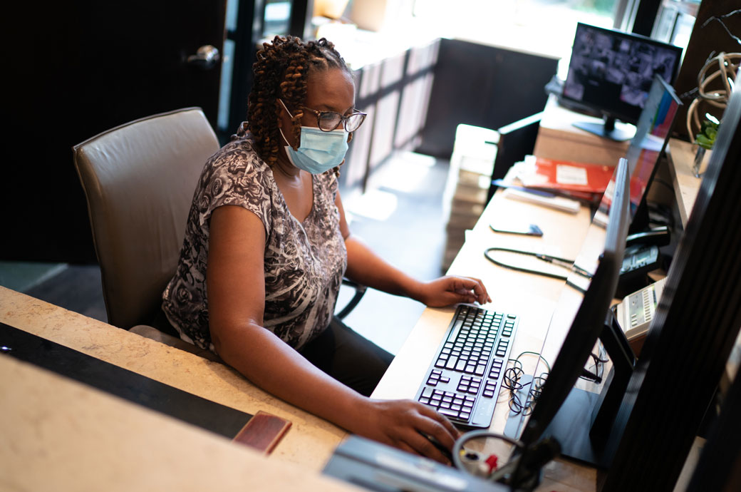 A woman works at a computer behind the desk, July 2020. (Getty/Sarah L. Voisin)
