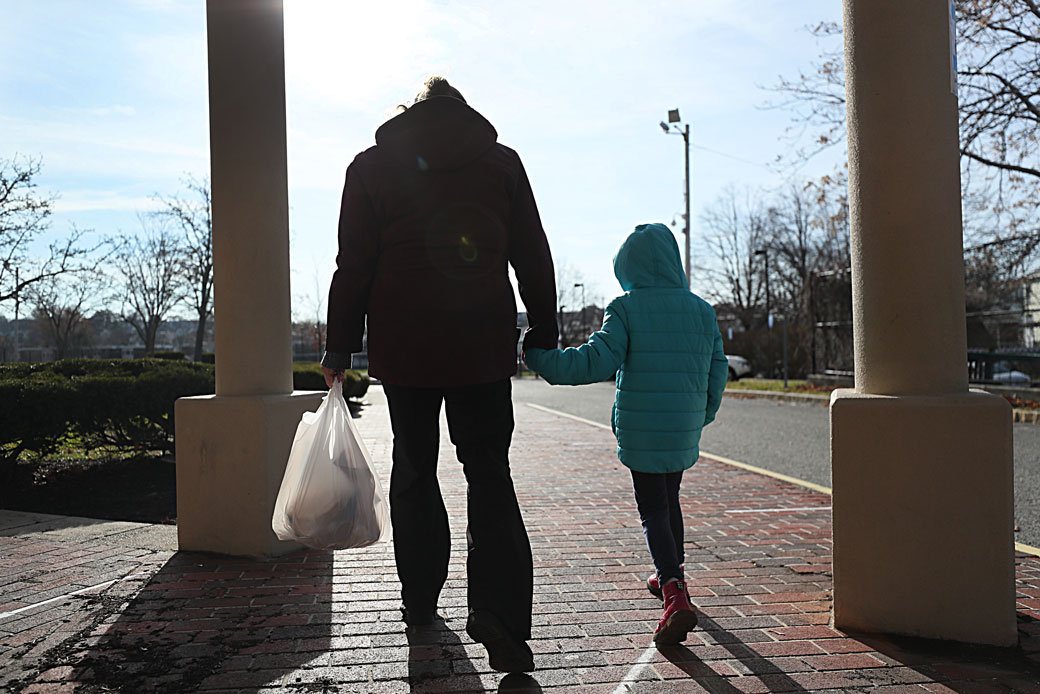 A woman walks with her daughter after picking up her breakfast and lunch in Revere, Massachusetts, on December 11, 2020. She is among many low-income parents in Massachusetts who have struggled to receive their promised free school meals during the COVID-19 pandemic. (Getty/The Boston Globe/Suzanne Kreiter)