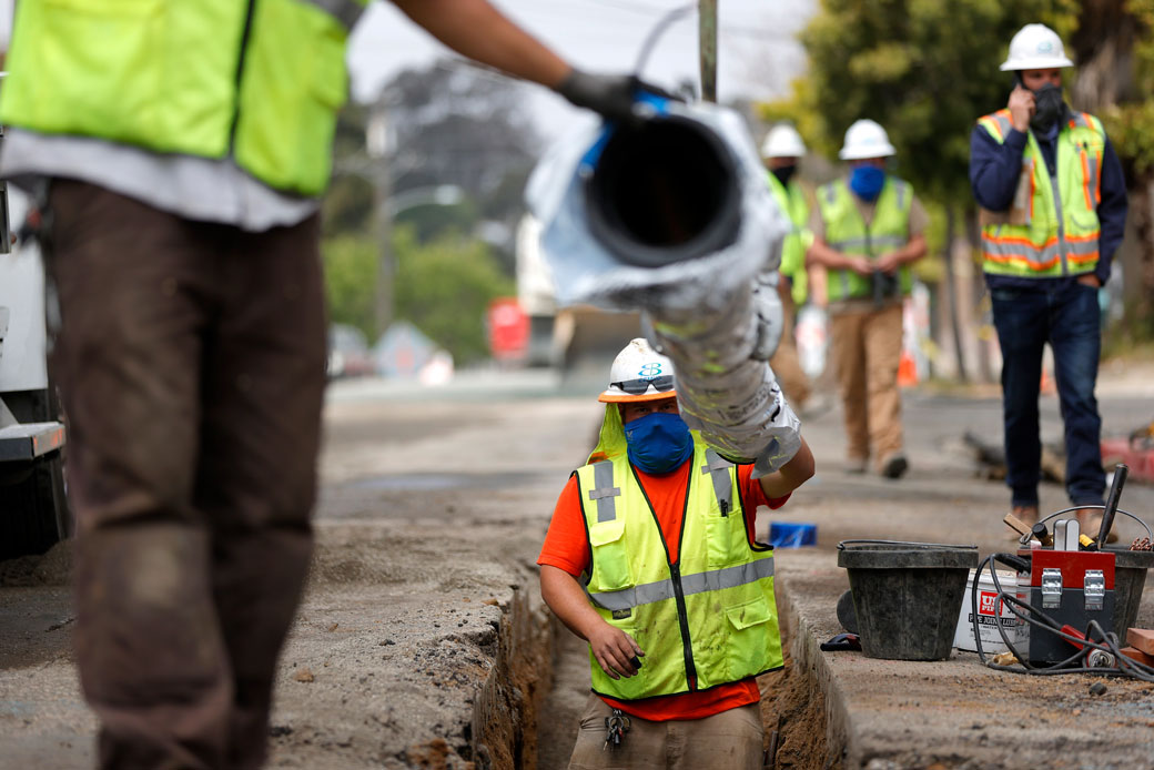  (Construction workers install a new water pipe in Oakland, California, April 2021.)