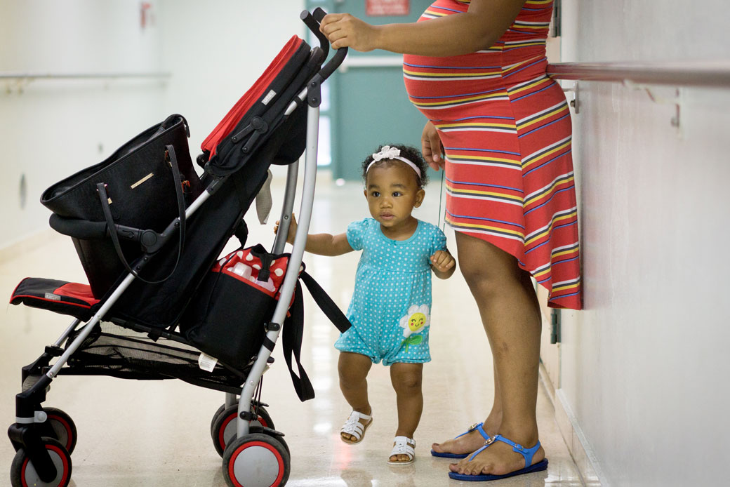 An expectant mom waits in a hallway with her 1-year-old daughter in Loiza, Puerto Rico, on August 30, 2016. (Getty/Angel Valentin)