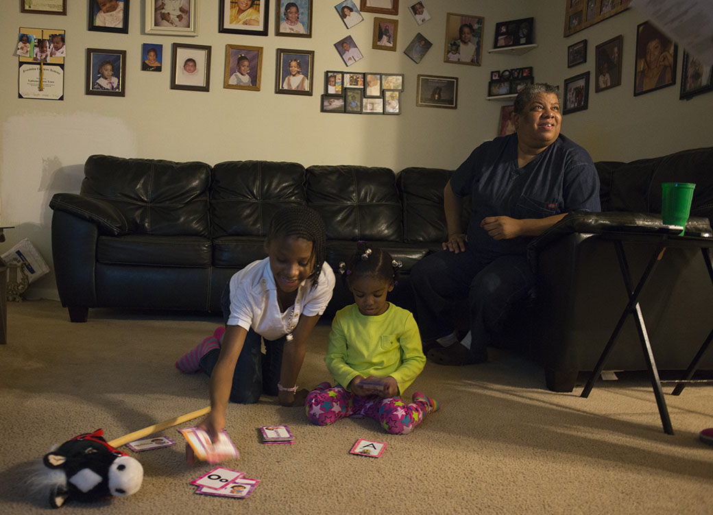 A disabled woman is photographed in her Washington, D.C., apartment, which she can barely afford with public assistance, with family members, October 2012. (Getty/The Washington Post/Marvin Joseph)