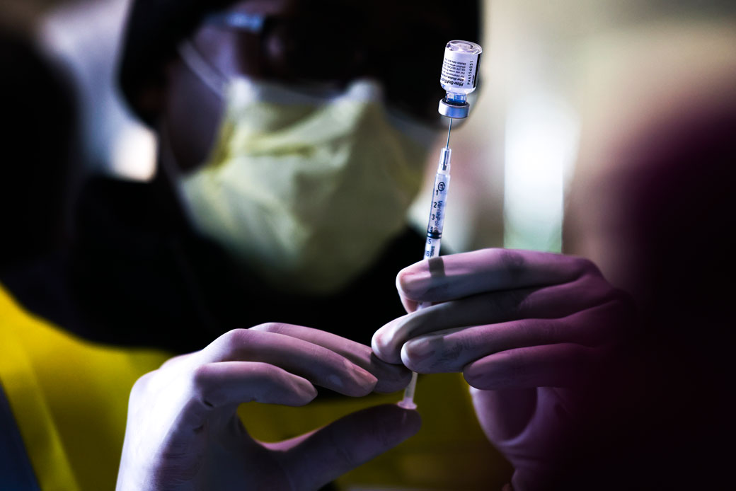 Pharmacy technicians prepare doses of the Pfizer-BioNTech vaccine at a mass COVID-19 vaccination event on January 30, 2021, in Denver.