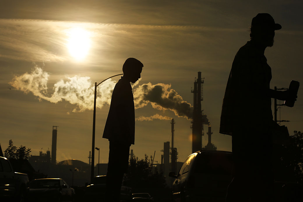 A child and his grandfather stand on their California street with an oil refinery seen in the background, March 2016. (Getty/Rick Loomis/Los Angeles Times)