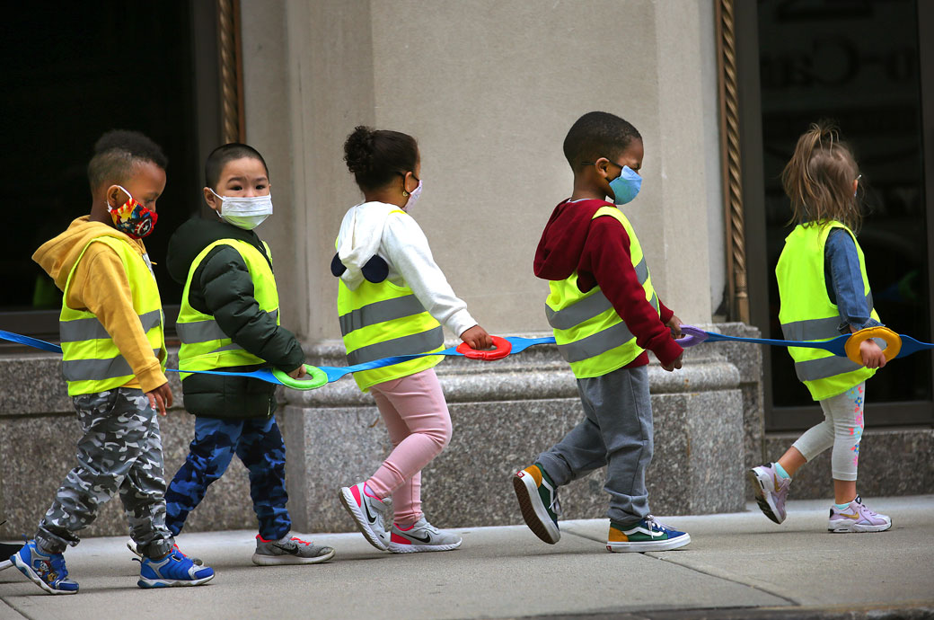 Youngsters wear vests and masks and hold on to a strap as they take a walk outdoors, September 2020. (Getty/John Tlumacki)