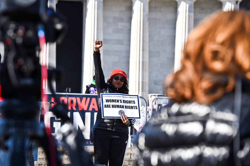 Rachel Bryan of the International Brotherhood of Electrical Workers holds a sign next to the podium in front of the Lincoln Memorial on the anniversary of the Women's March, January 2018. (Getty/J.M. Giordano)