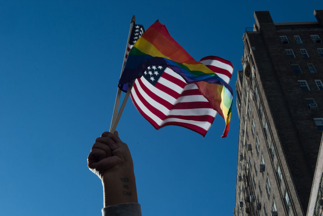 People hold signs and flags in front of the Stonewall Inn in New York during a rally in support of immigrants, asylum-seekers, refugees, and the LGBTQI community, February 2017. (Getty/AFP/Bryan R. Smith)