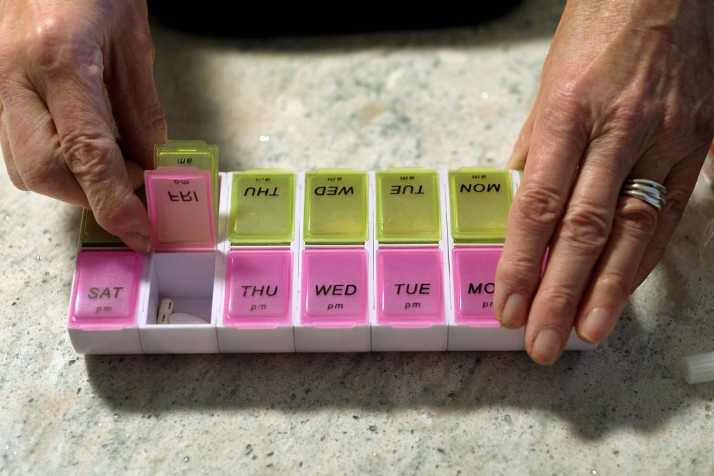 (A woman displays her pill organizer that she uses to keep track of the prescription drugs, vitamins, insulin, and arthritis injections she takes at her home in Medford, Massachusetts, January 2020.)